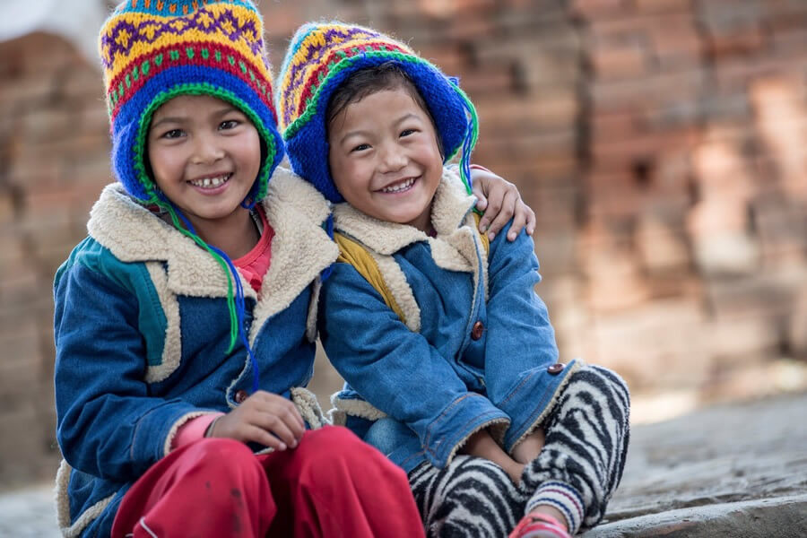 actionaid χαμογελαστά παιδιά με μπλε σκουφιά κάθονται αγκαλιά