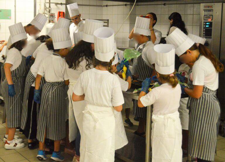 filoitoupediou.gr μικρά παιδιά σε κουζίνα  εστιατορίου κάνουνε μάθημα μαγειρικής με στολές και καπέλα σεφ  | YouBeHero