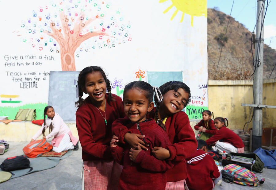 actionaid.gr παιδιά στην Αφρική χαμογελάνε παίζουνε στο διάλειμμα με ζωγραφισμένο τον τοίχο πίσω τους  | YouBeHero