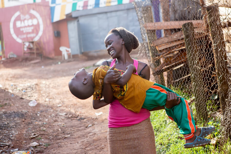 actionaid.gr μητέρα στην Αφρική κρατάει το παιδί της αγκαλιά χαρούμενη | YouBeHero