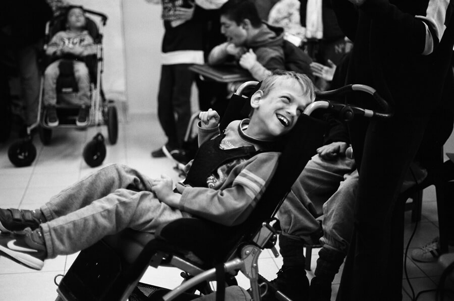 amimoni.gr παιδάκι σε ειδικό αναπηρικό αμαξίδιο χαμογελάει   | YouBeHero