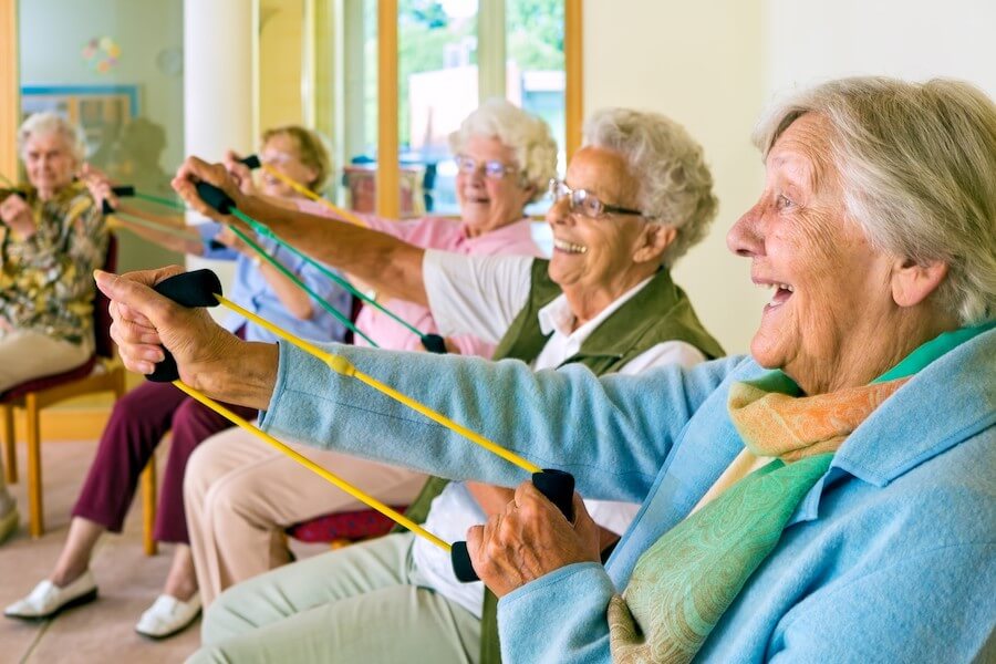 frodizo.gr  ηλικιωμένες γυναίκες κάνουνε ασκήσεις με λάστιχα  σε κατ'οίκον παρέμβαση για την άνοια   | YouBeHero